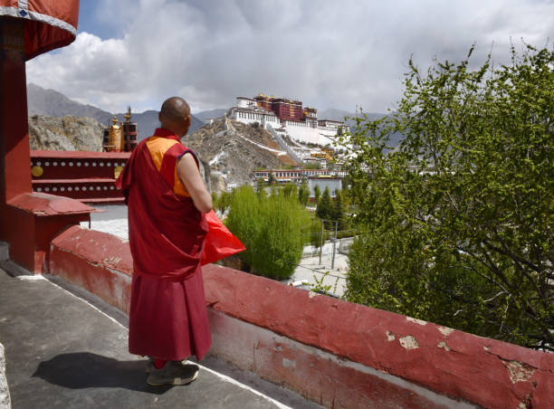A Buddhist monk stands on  a terrace overlooking The Potala Palace 
